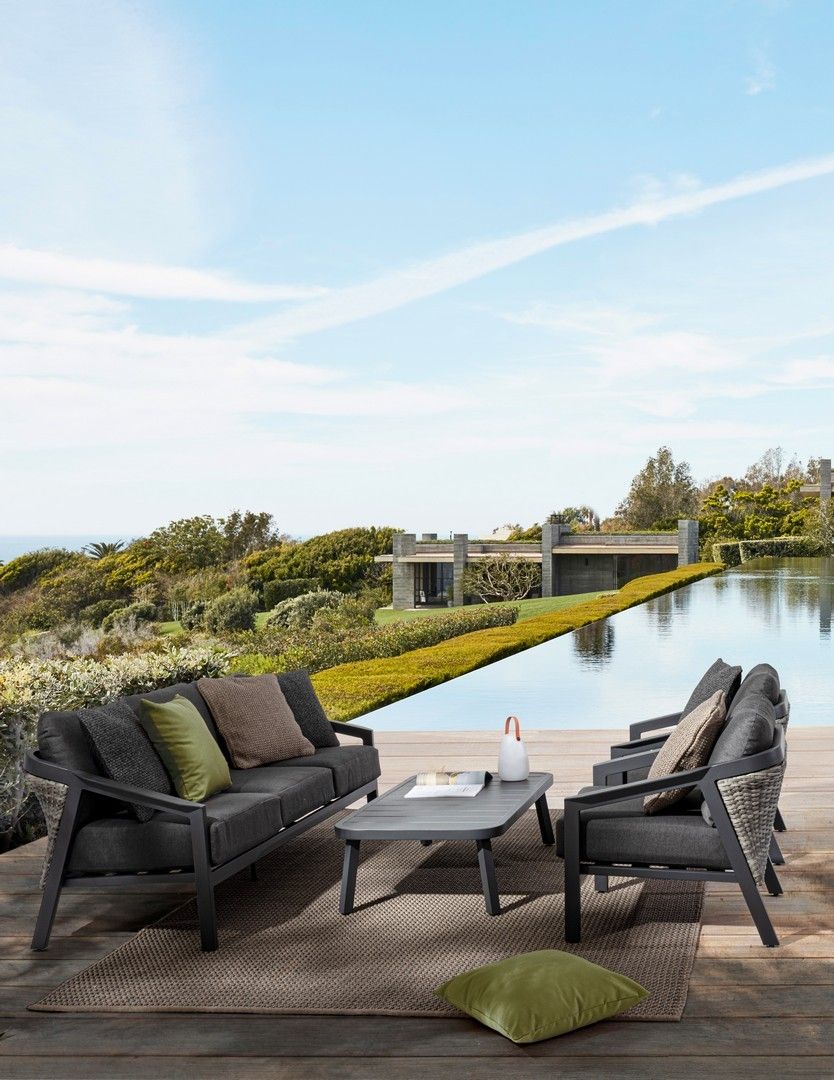 Un patio con un divano, sedie e un tavolo accanto alla piscina.