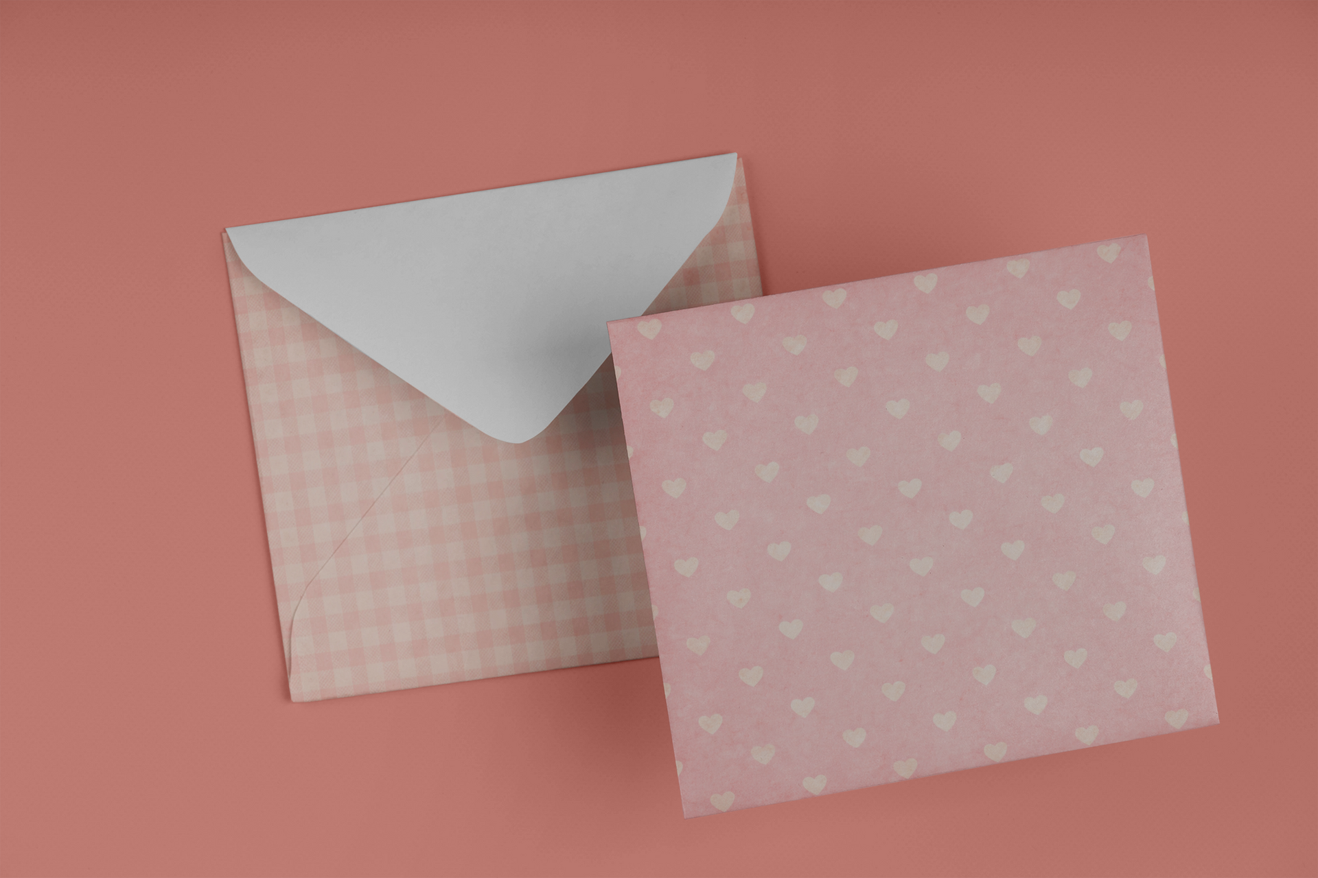 Two pink patterned envelopes on a pink background, one open with a white flap showing.