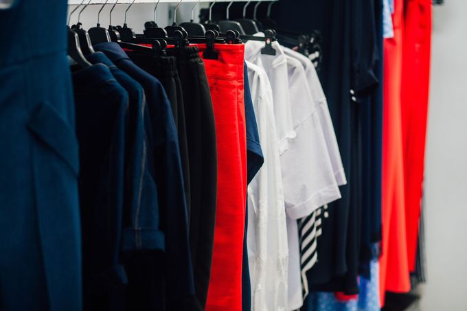 Appendiabiti con camicie scure, bianche, rosse e a righe appese in un negozio.