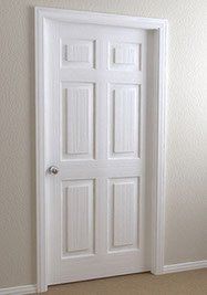 White, six-panel interior door in a white frame, set in a beige wall. Silver doorknob is visible.