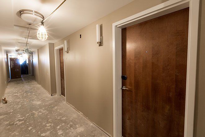 Hallway with tan walls, brown doors, and exposed concrete floor.