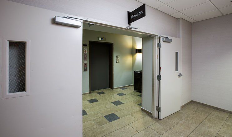 Hallway with two white doors, one open, leading to an elevator.