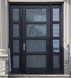 Black front door with sidelights, featuring frosted glass panels.