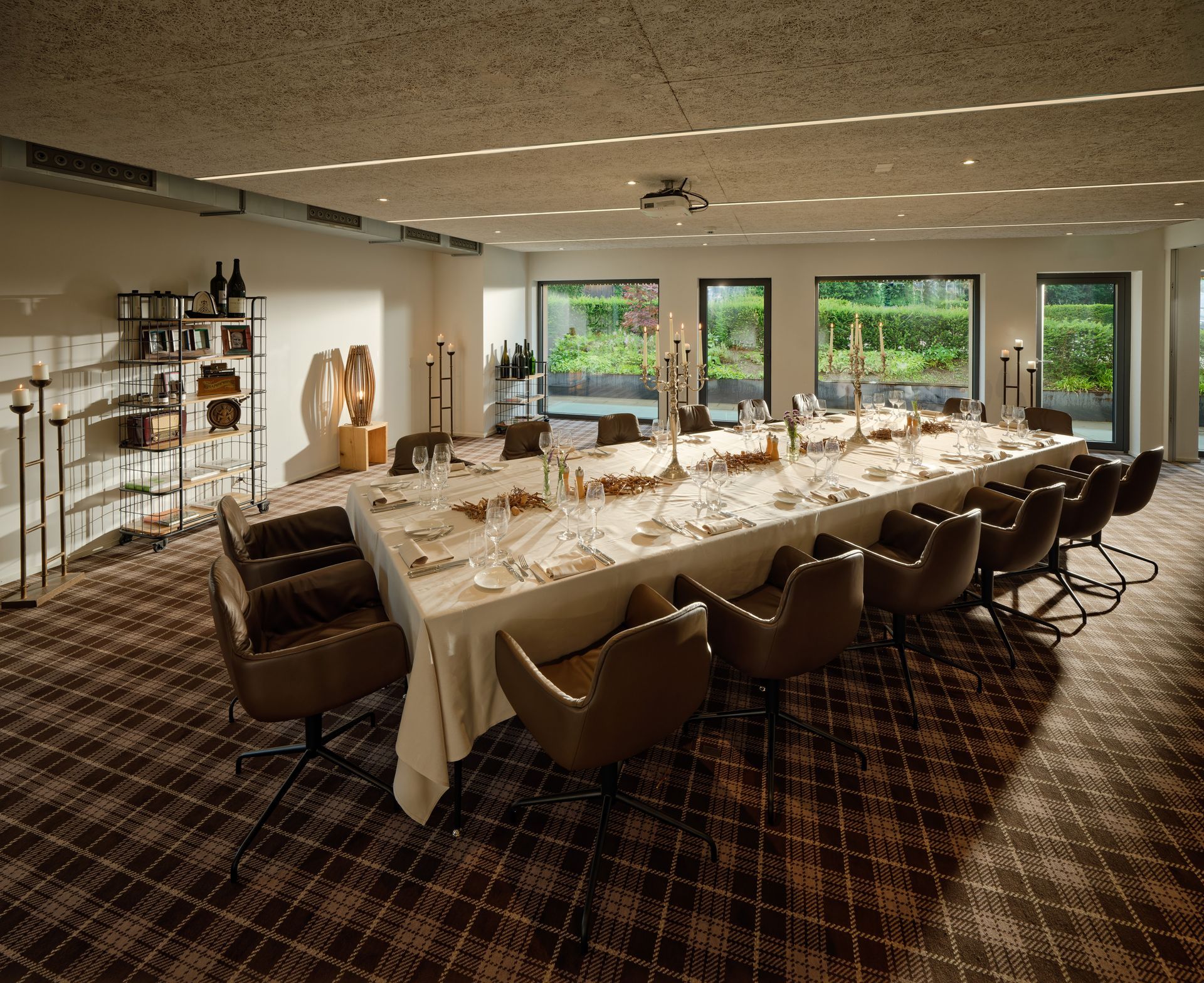 Elegantes Esszimmer mit langem Esstisch, braunen Stühlen und großen Fenstern mit Blick ins Grüne.