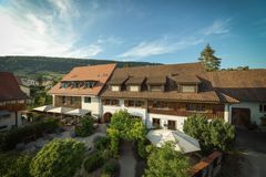 Rustikales Hotel am Hang mit Terrakotta-Dächern, Balkonen und üppigem Grün unter blauem Himmel