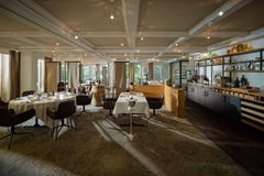 Elegantes Restaurant mit gedeckten Tischen, warmem Licht und einer Bar an der rechten Wand