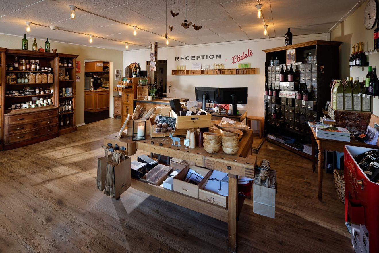 Gemütliches Ladeninterieur mit Holztischen, Warenregalen und warmen Lichterketten