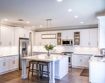 A kitchen with white cabinets , stainless steel appliances , and a large island.