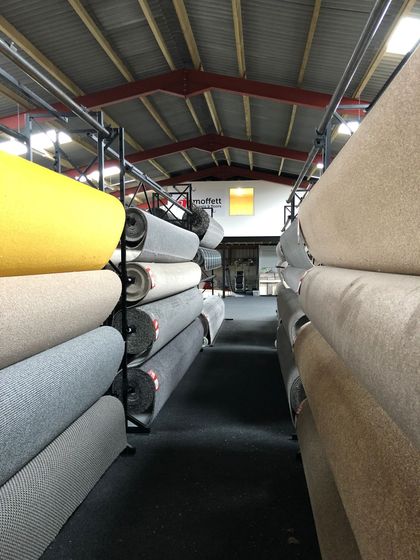 A warehouse filled with rolls of carpet stacked on top of each other.