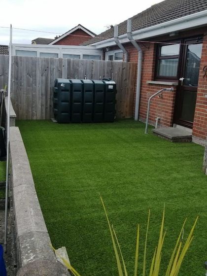 A backyard with a fence and a green water tank.