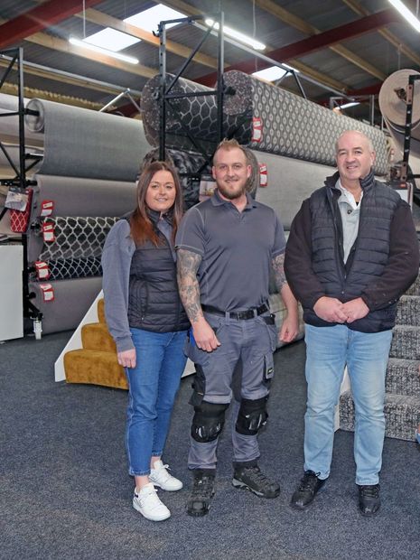 A group of people are posing for a picture in a carpet store.