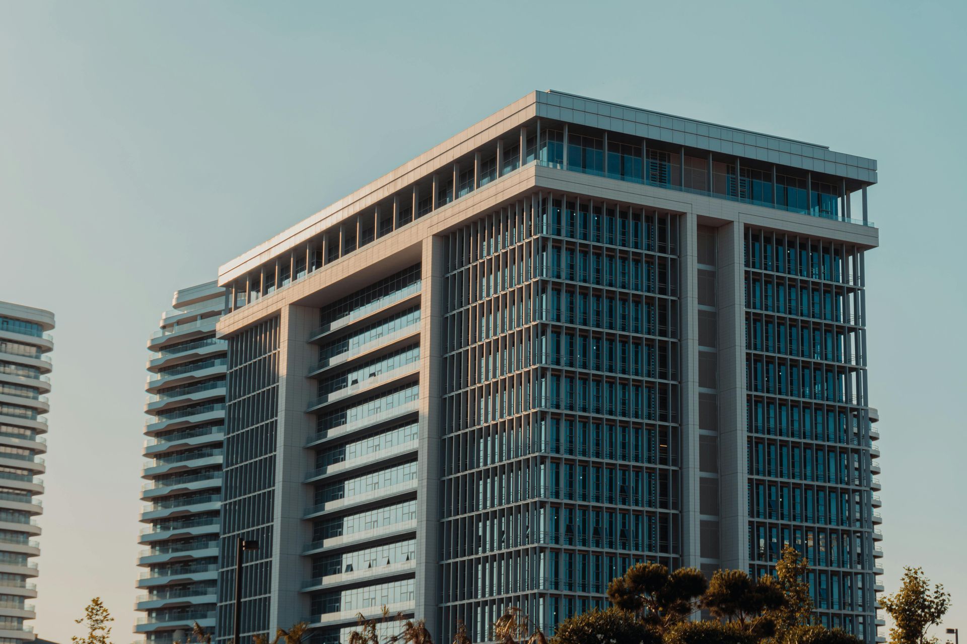 Modern high-rise building with glass windows reflecting the clear blue sky; exterior daytime shot.