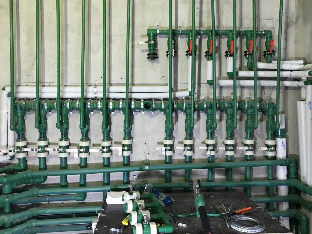 Tuberías y válvulas verdes en un cuarto de servicio.