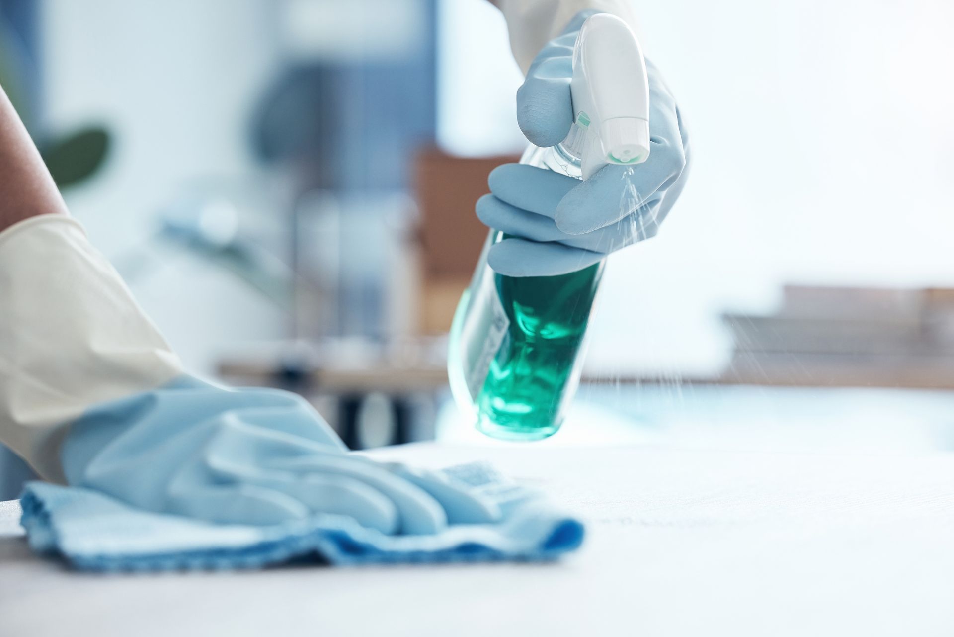 A person is cleaning a table with a spray bottle and a cloth.
