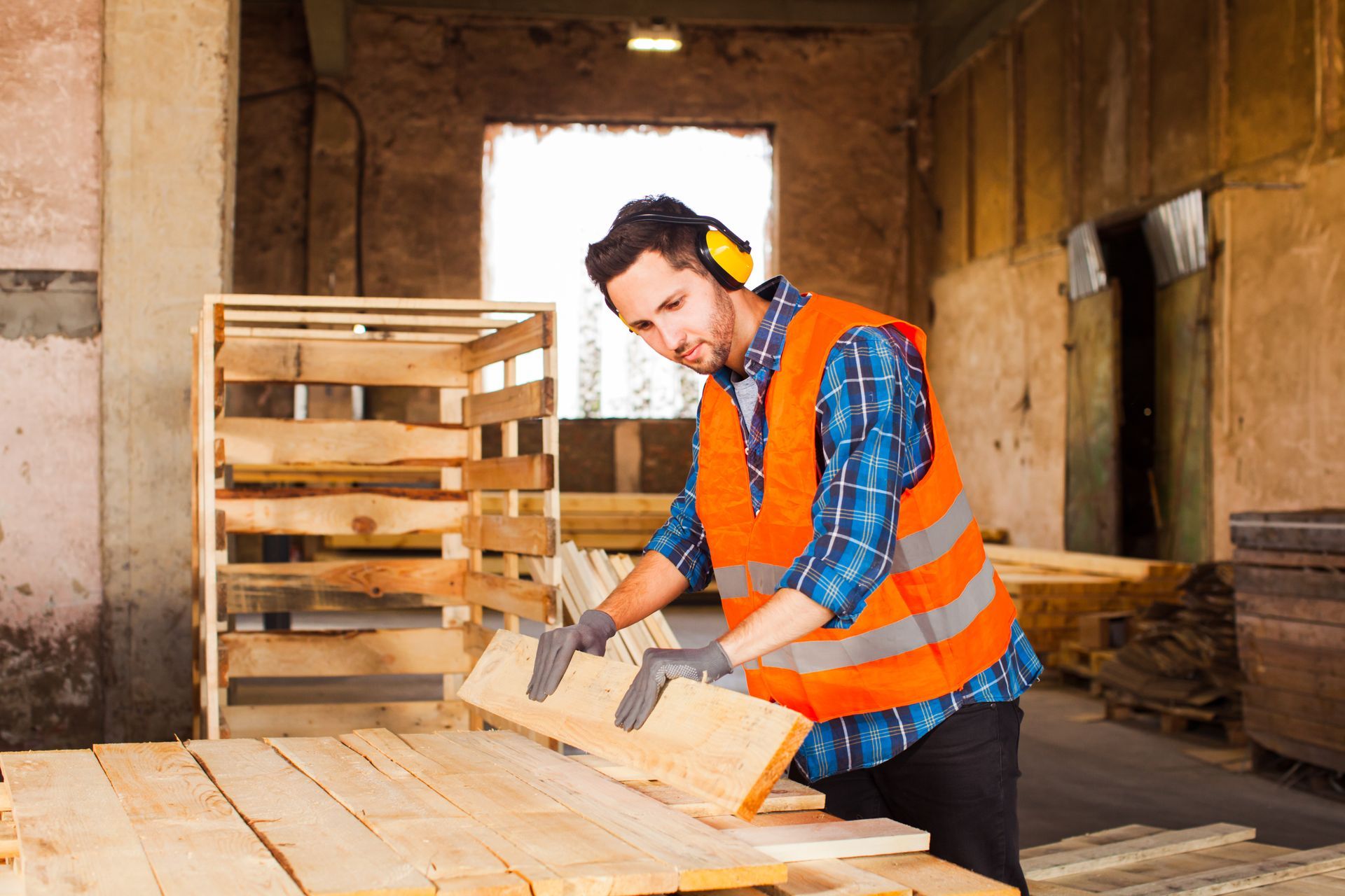 A man is cutting a piece of wood in a factory.