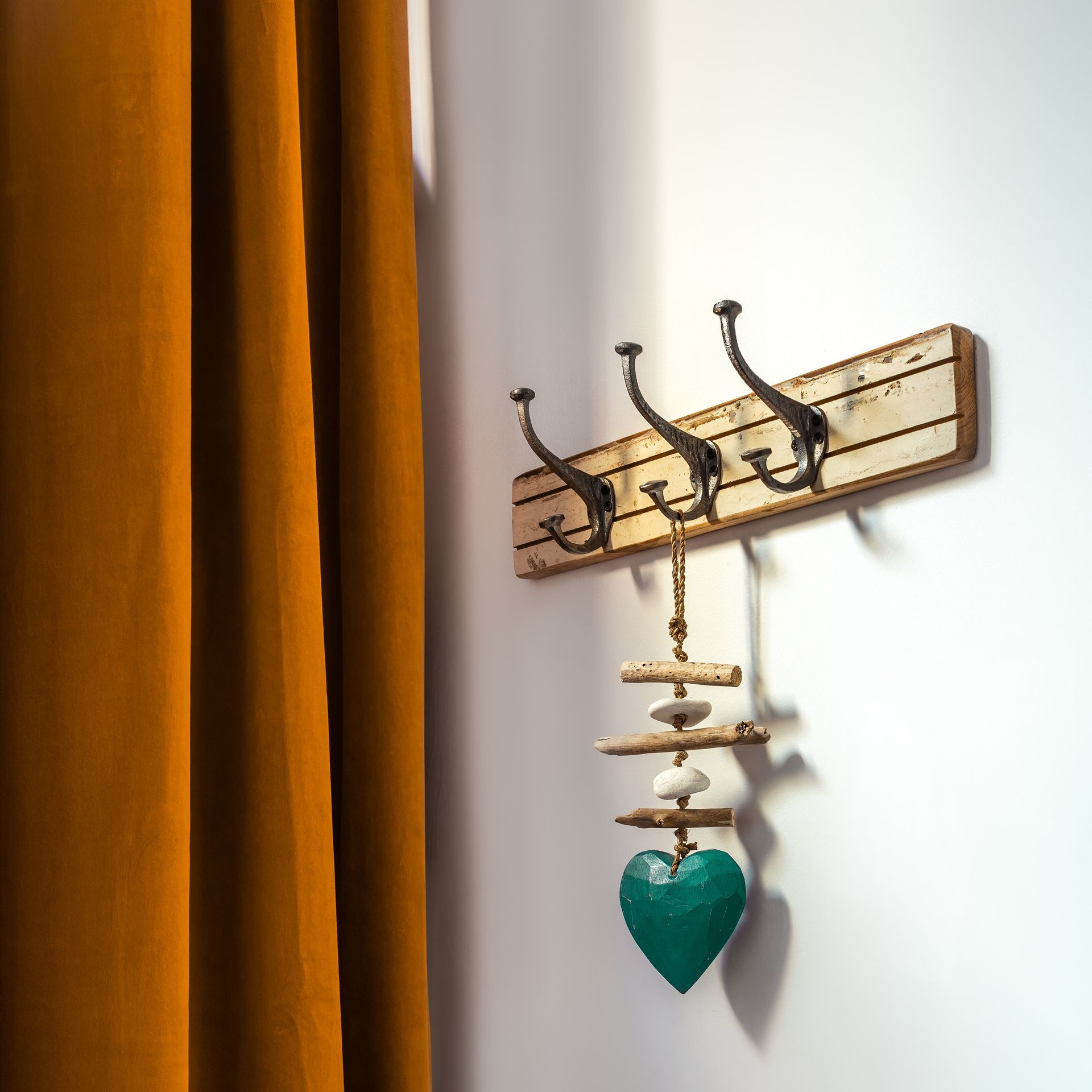 A green heart is hanging from a hook on a wall