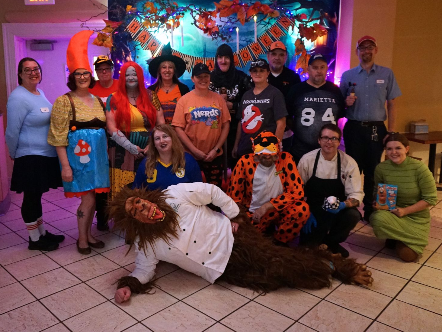 Group of people in Halloween costumes posing in front of decorations.