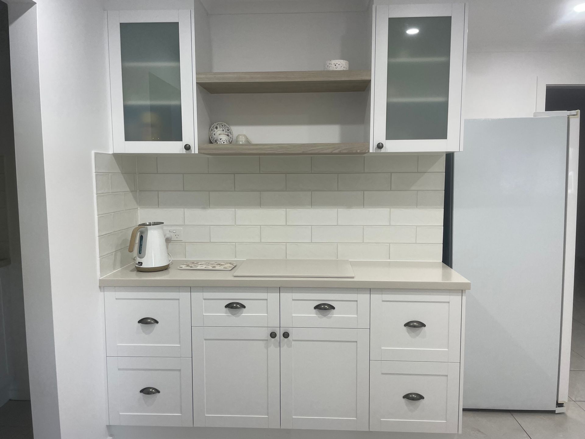 A kitchen with white cabinets and a white refrigerator