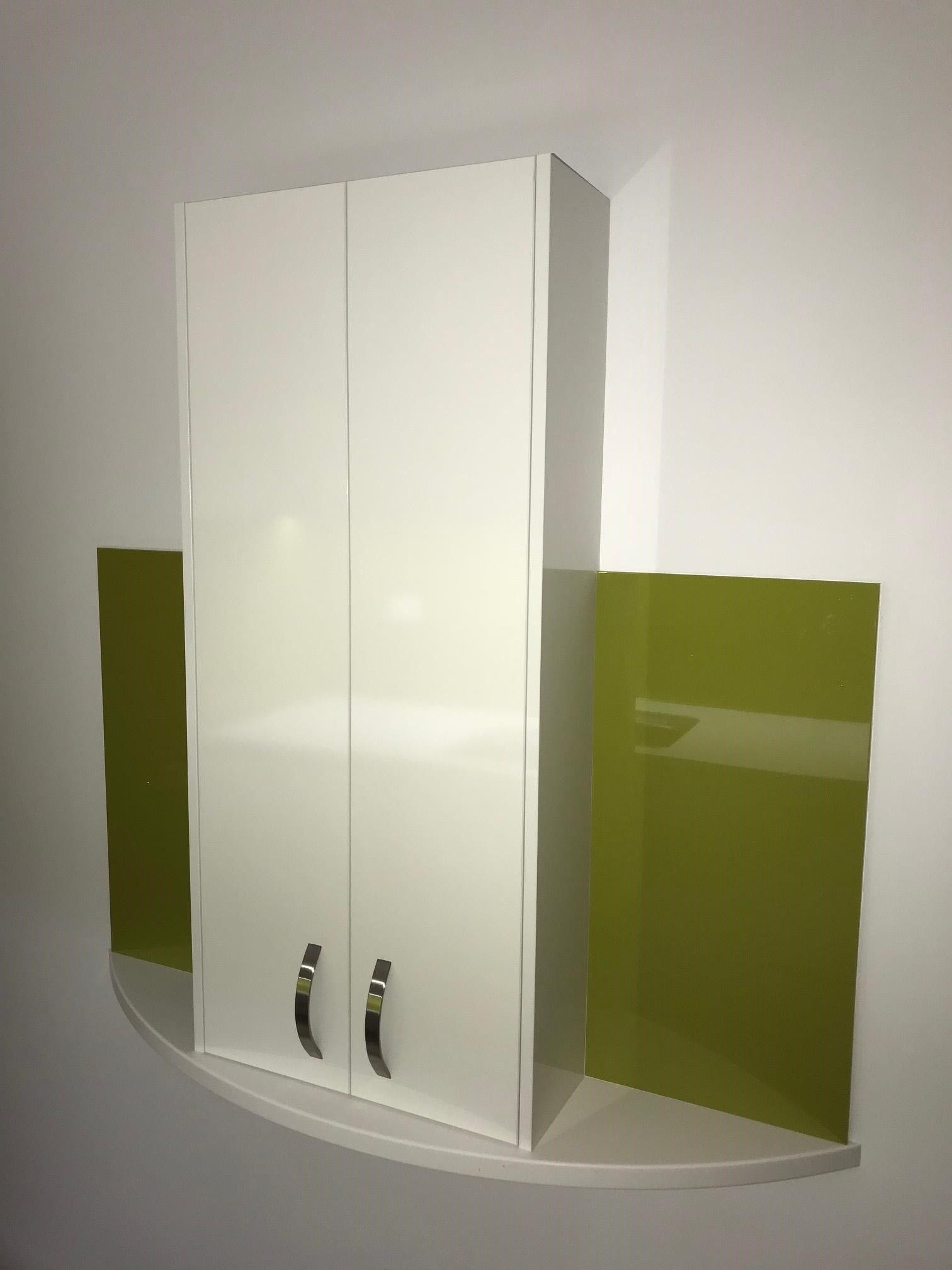 A white cabinet is hanging on a wall next to a green wall.