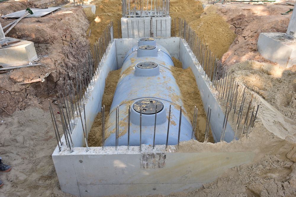 A Large Concrete Tank is Sitting in the Dirt in a Trench — Bennett's Servicing and Plumbing In Berry, NSW