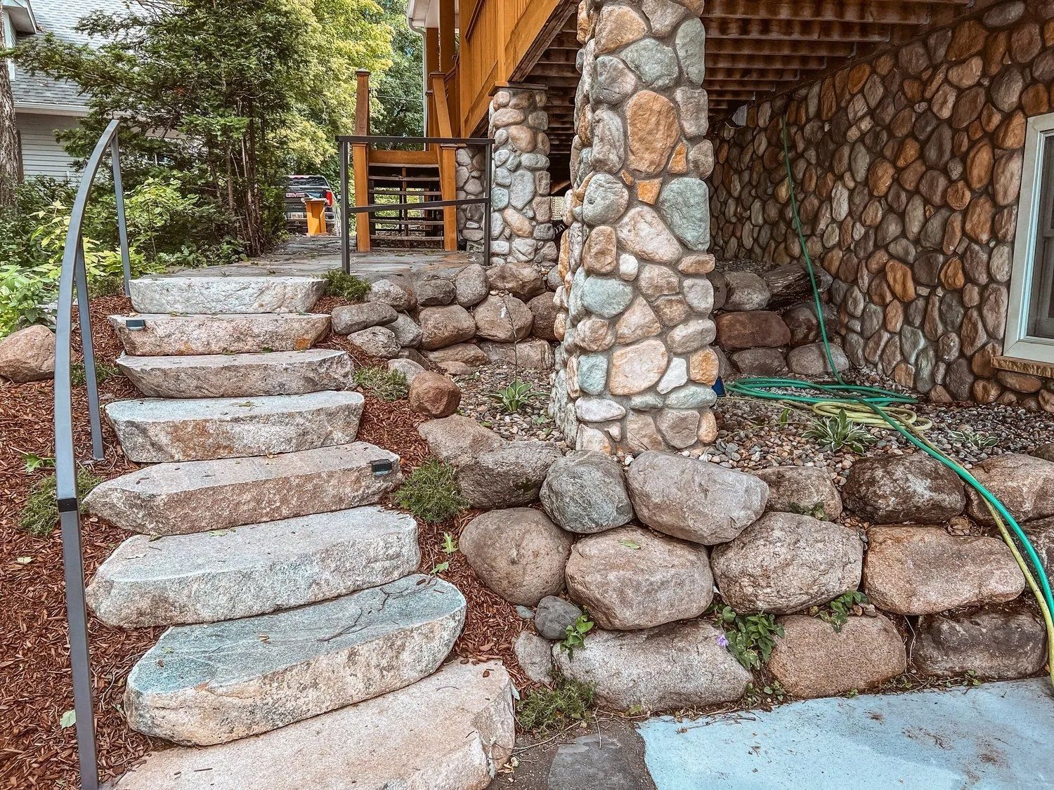 Stone steps leading up to a house with a stone and wood facade.