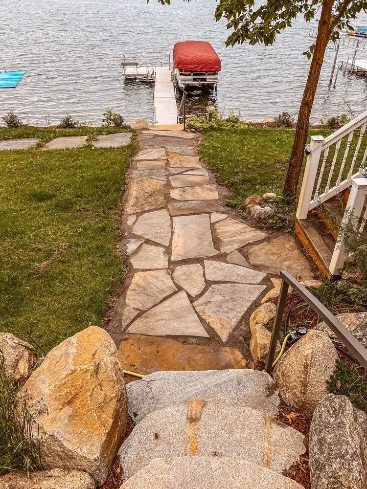Stone path and steps leading to a dock with a boat on a lake.