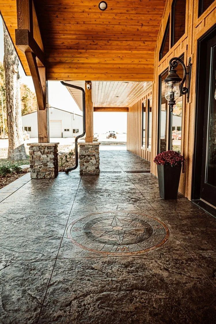 Covered porch with stamped concrete floor, wooden ceiling, and stone columns.