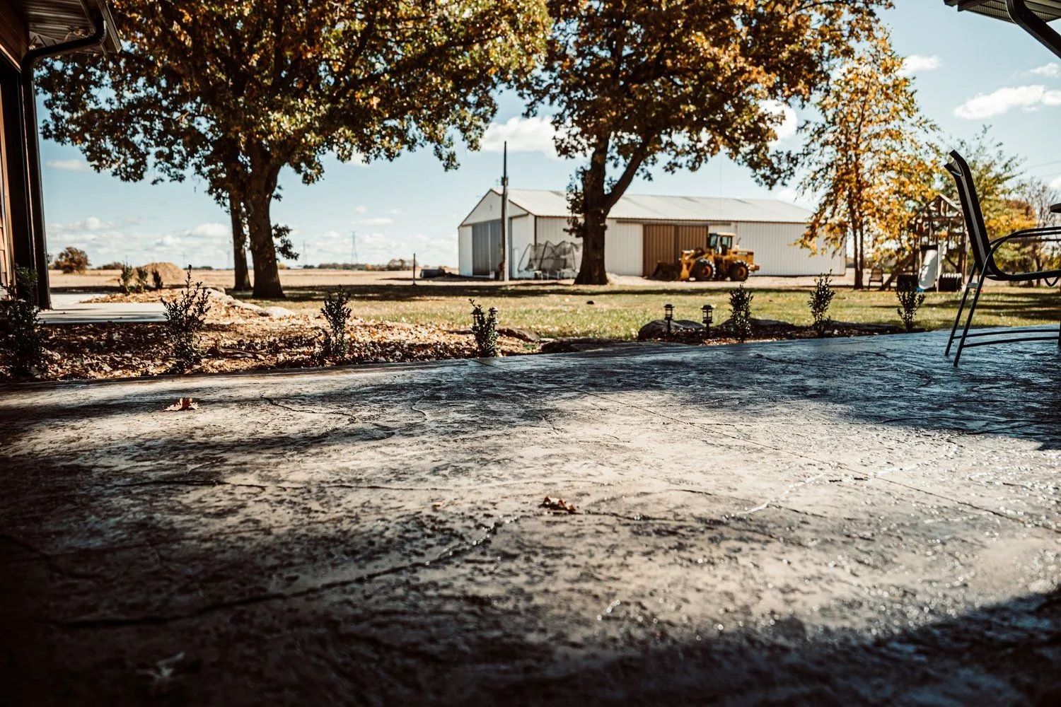 Patio view of a farm with a barn, trees, and blue sky.