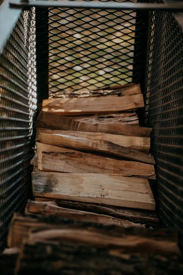 Firewood stacked inside a metal mesh container.