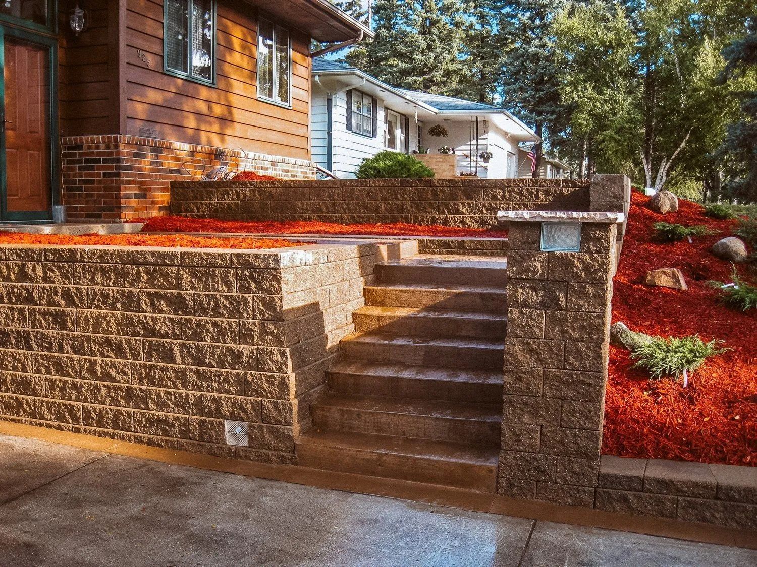 Brick steps leading up to a house with red mulch landscaping.