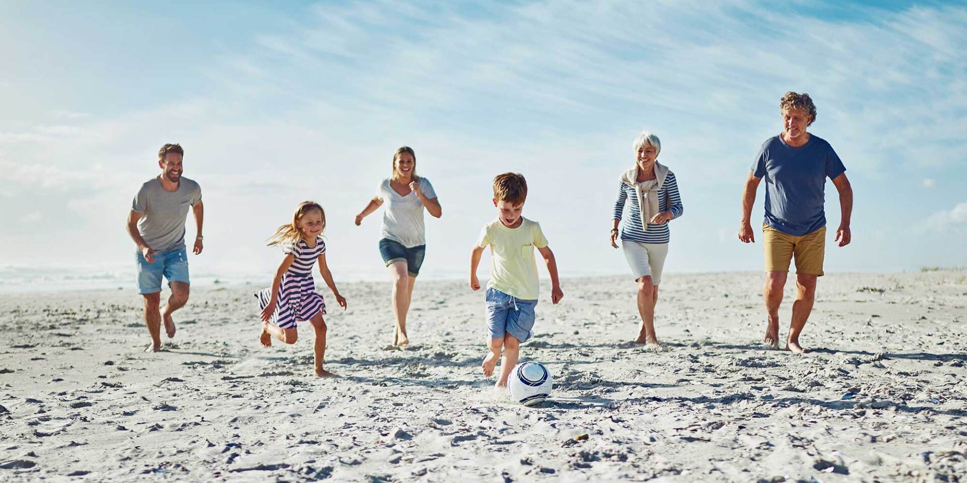 family playing soccer on the beach