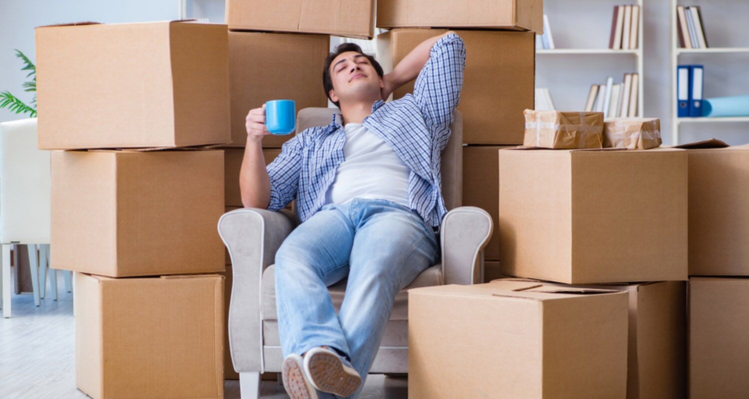 Man is Sitting in a Chair Surrounded by Cardboard Boxes — Bargara Removals in Rubyanna, QLD