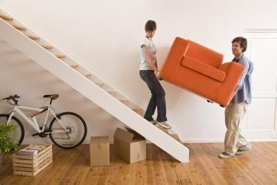 Man and a Woman Are Carrying an Orange Chair Up a Set of Stairs — Bargara Removals in Rubyanna, QLD