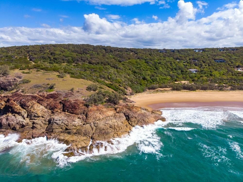 An Aerial View of a Beach With Waves Crashing Against the Rocks — Bargara Removals in Gladstone, QLD