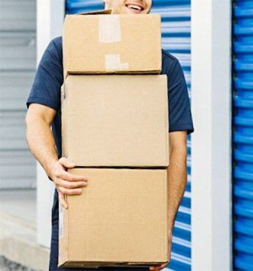 Man is Holding a Stack of Cardboard Boxes — Bargara Removals in Rubyanna, QLD