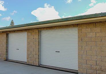 There Are Two Garage Doors on the Side of a Brick Building — Bargara Removals in Rubyanna, QLD