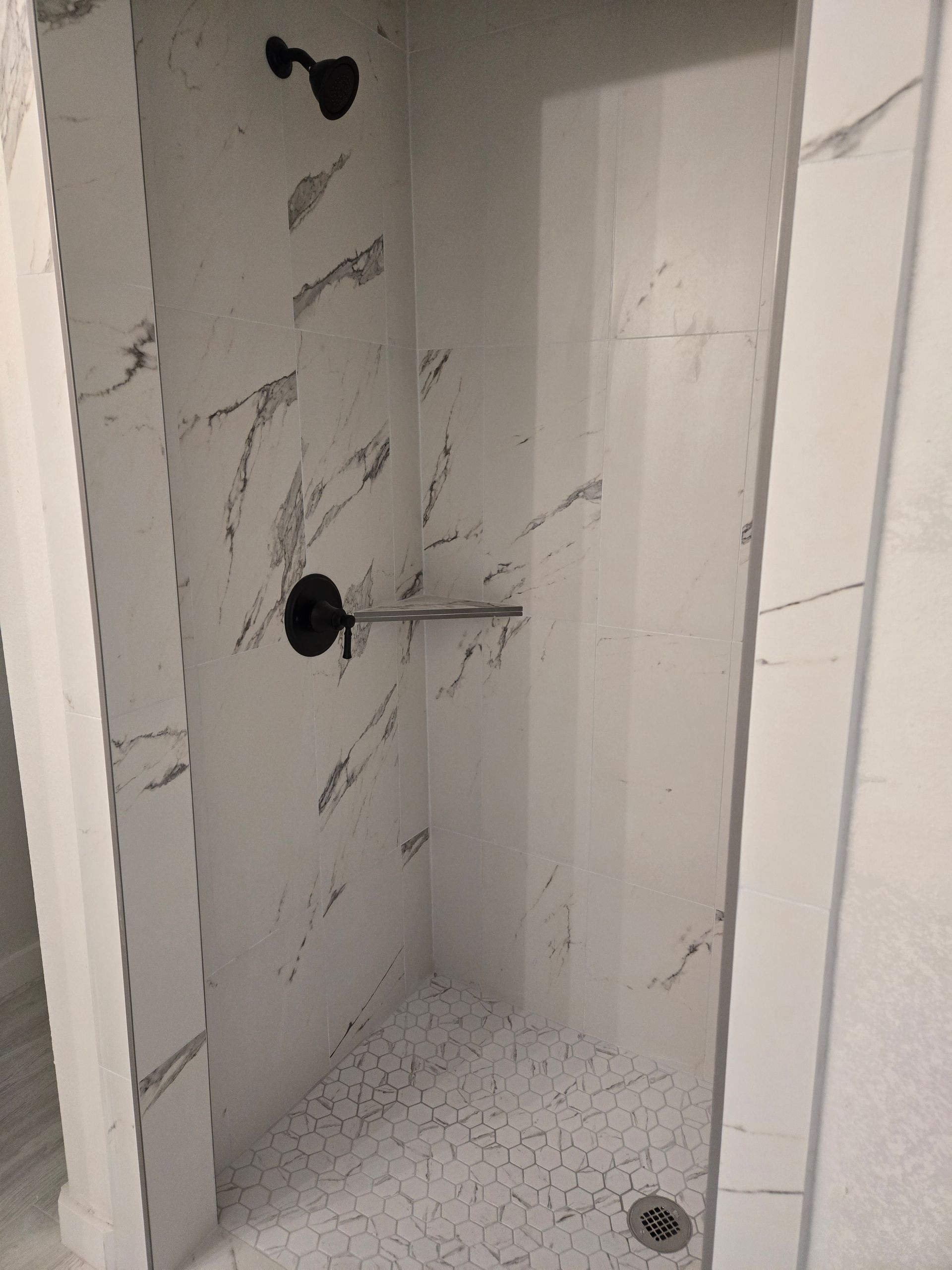 A bathroom with a walk in shower and a black shower head.