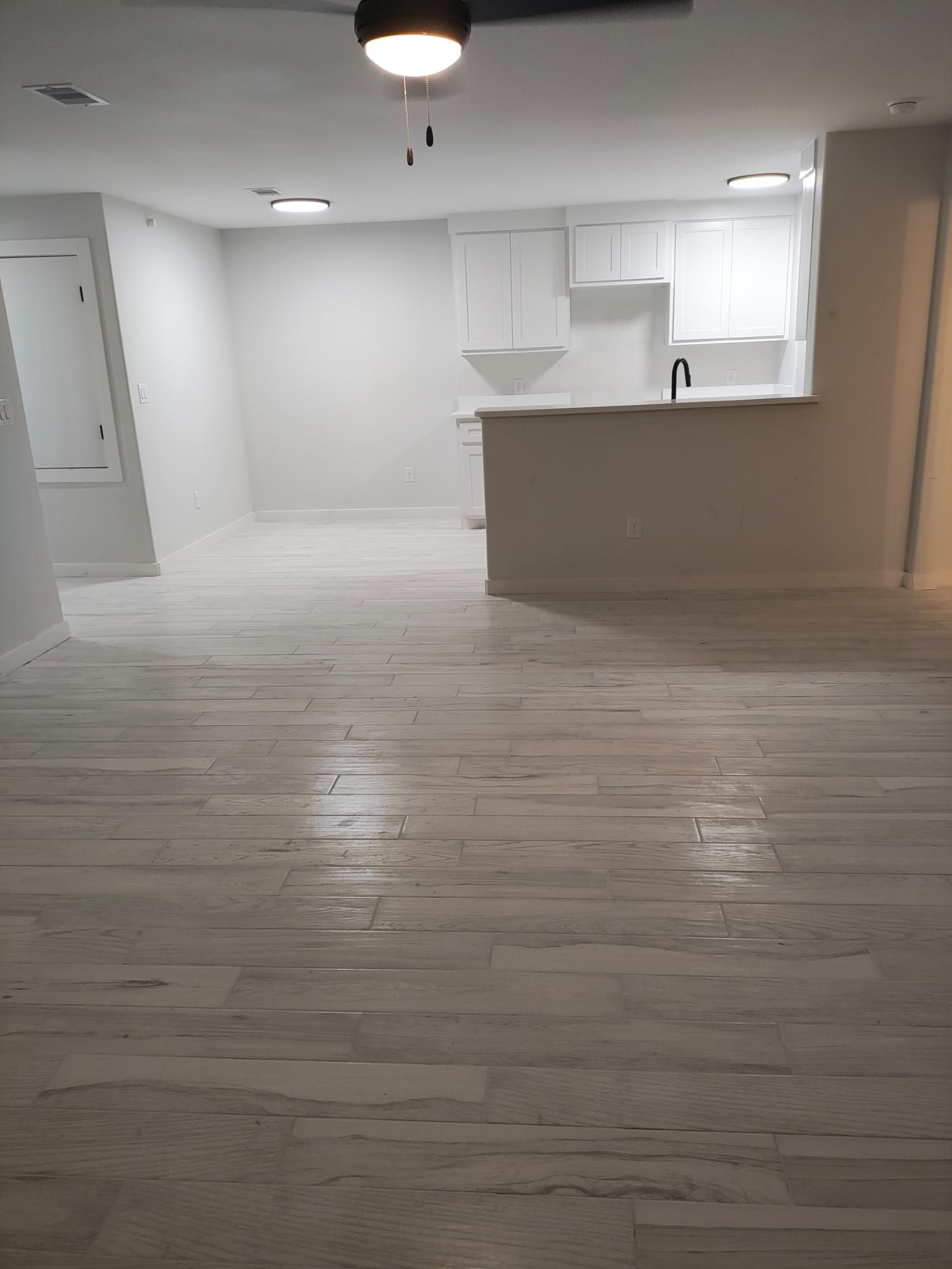 An empty room with a wooden floor and a ceiling fan.