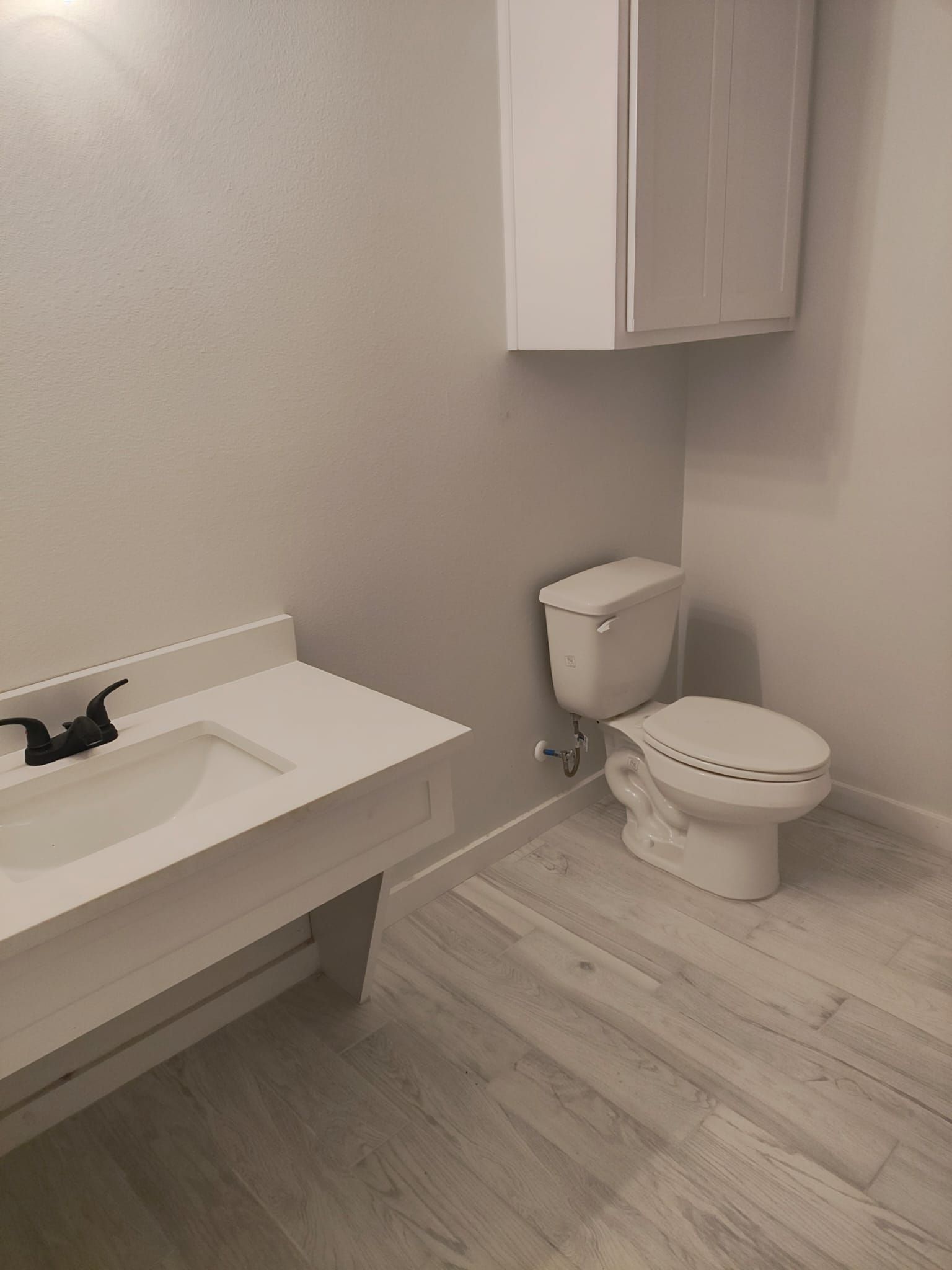 A bathroom with a sink , toilet and cabinet.