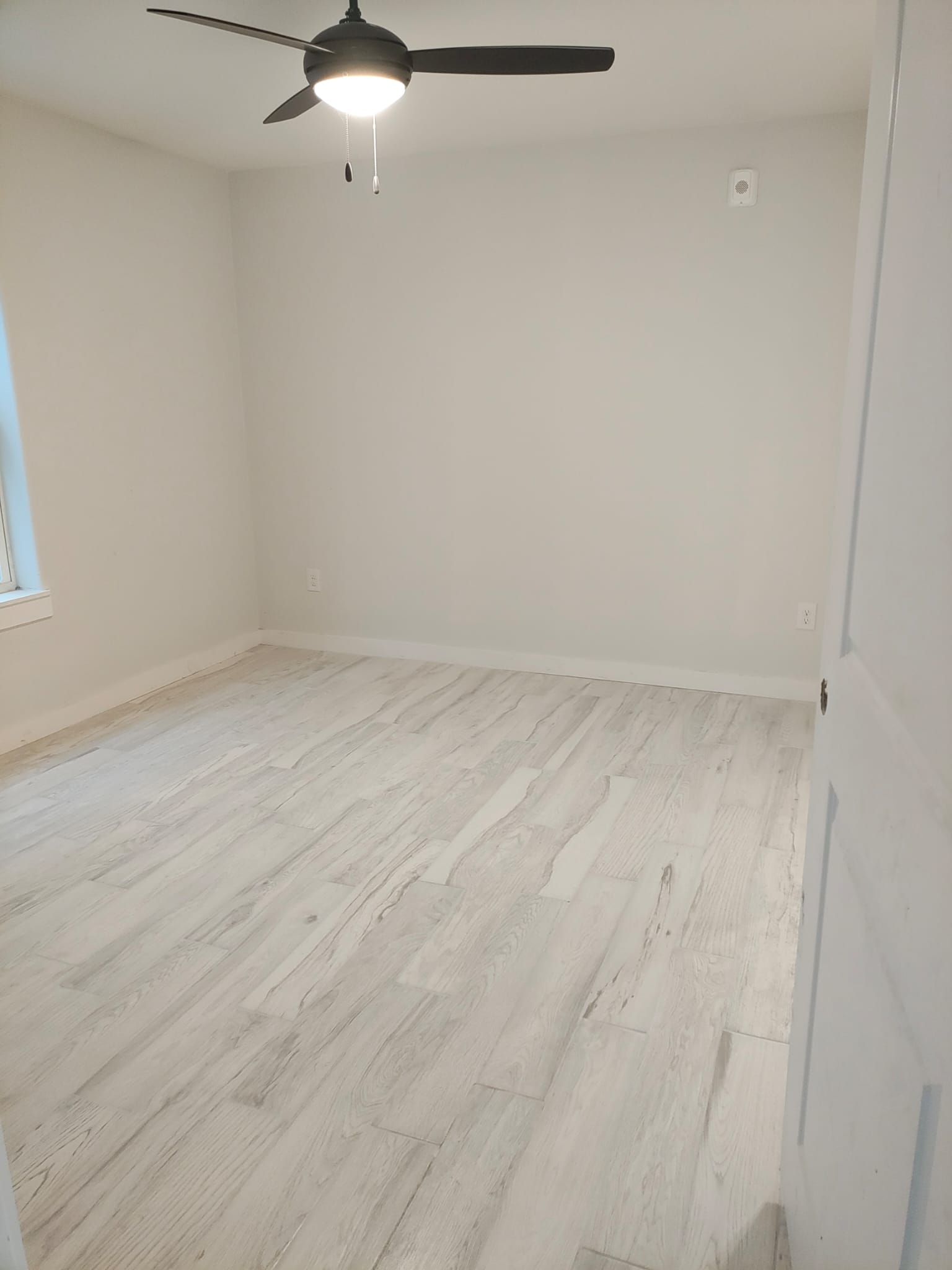 An empty room with a ceiling fan and a light on the ceiling.