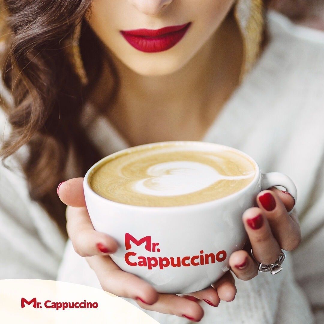 A woman with red lipstick is holding a cup of coffee.