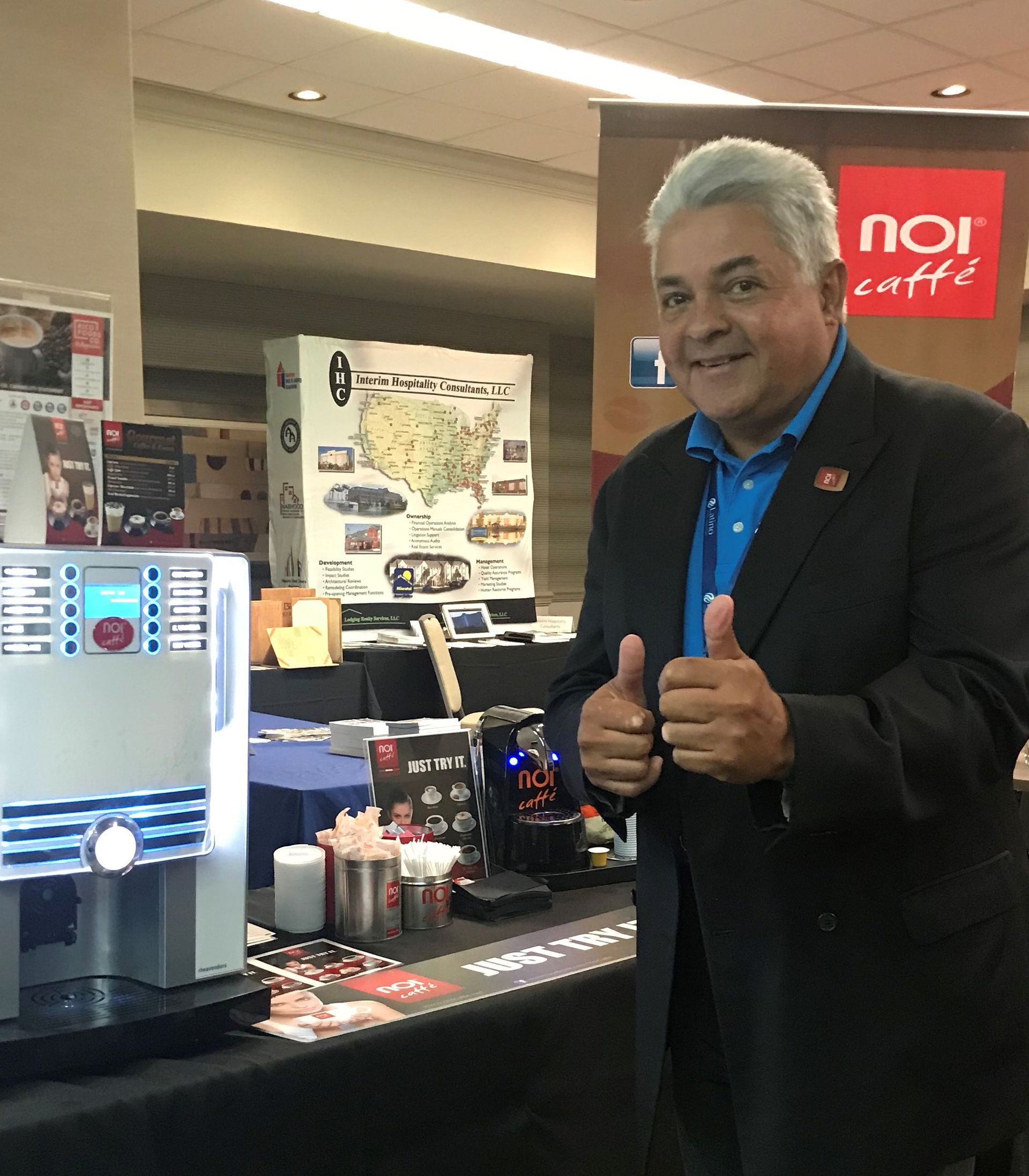 A man giving a thumbs up in front of a noi coffee machine