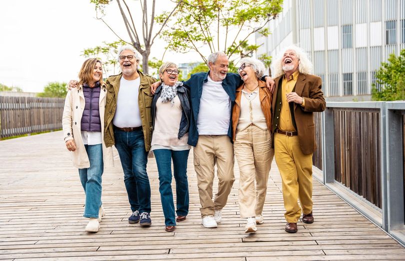 A group of elderly people are walking down a wooden bridge.