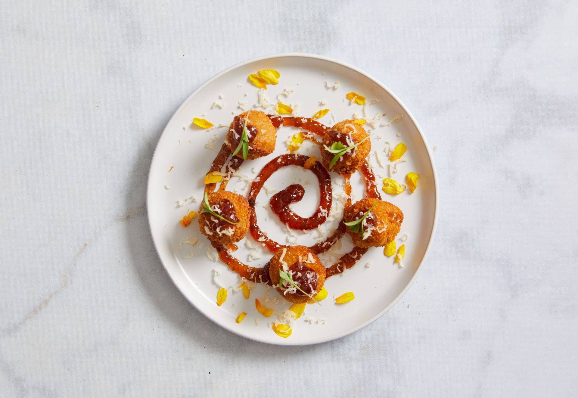 A white plate topped with fried food and sauce on a table.