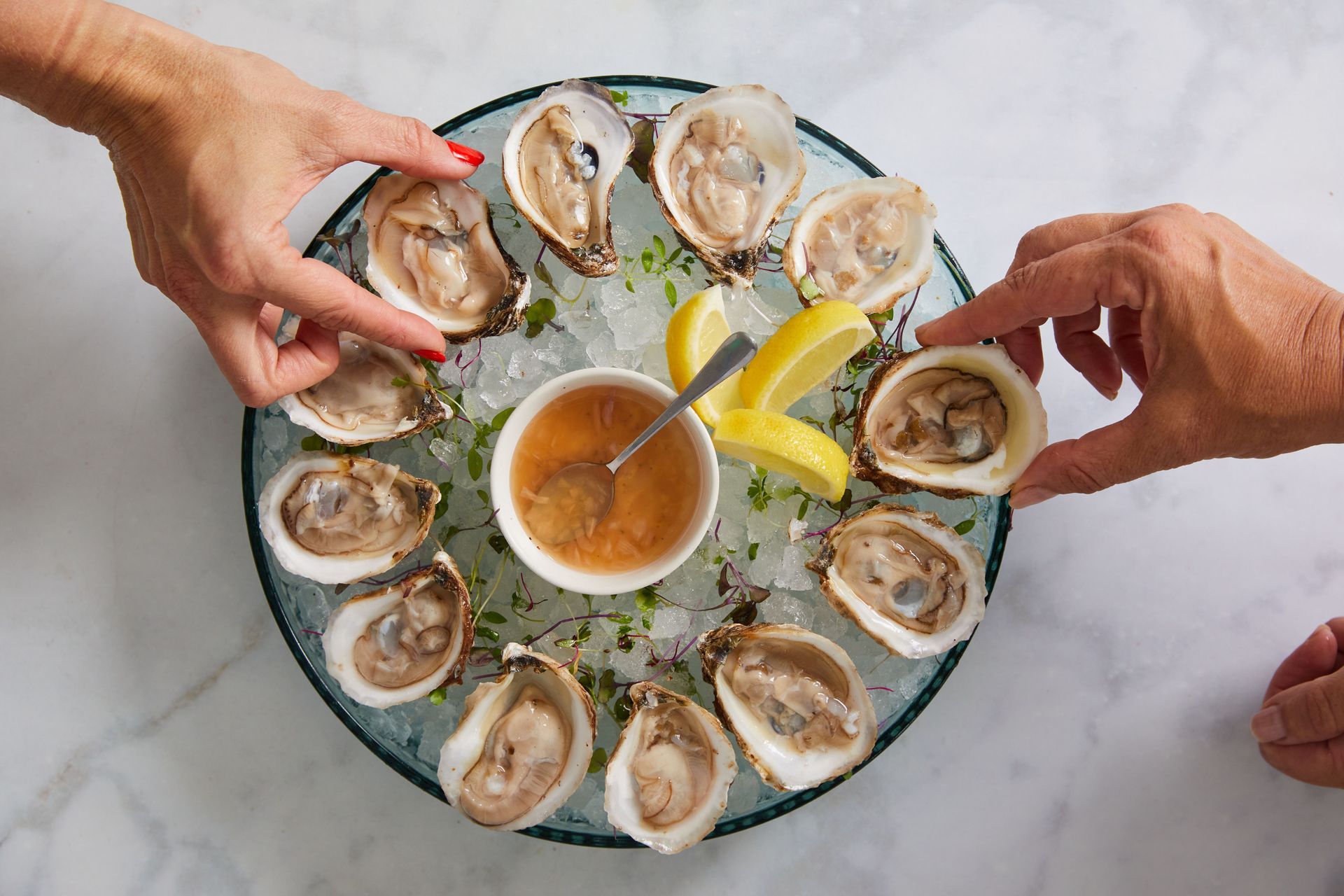 Two people are eating oysters on the half shell on ice.