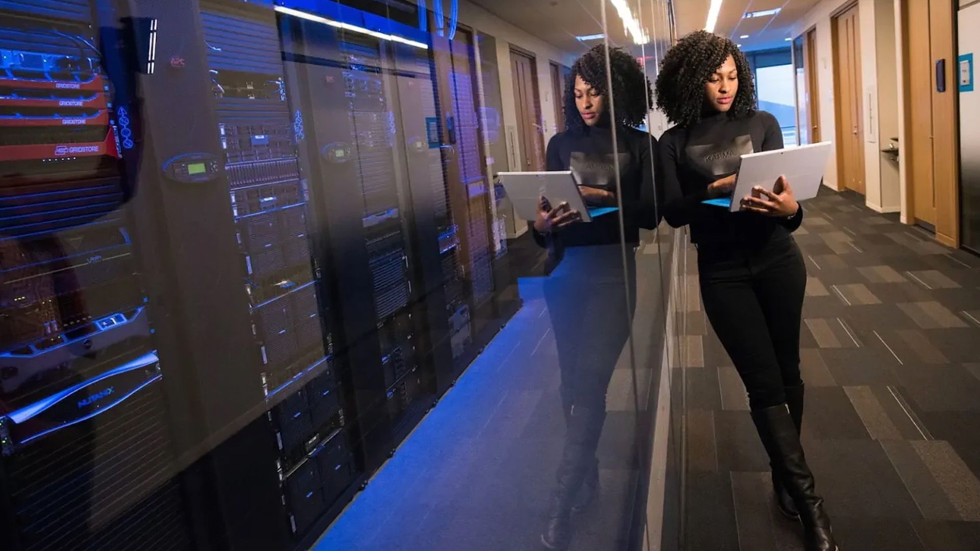 A woman is standing in a hallway holding a tablet.