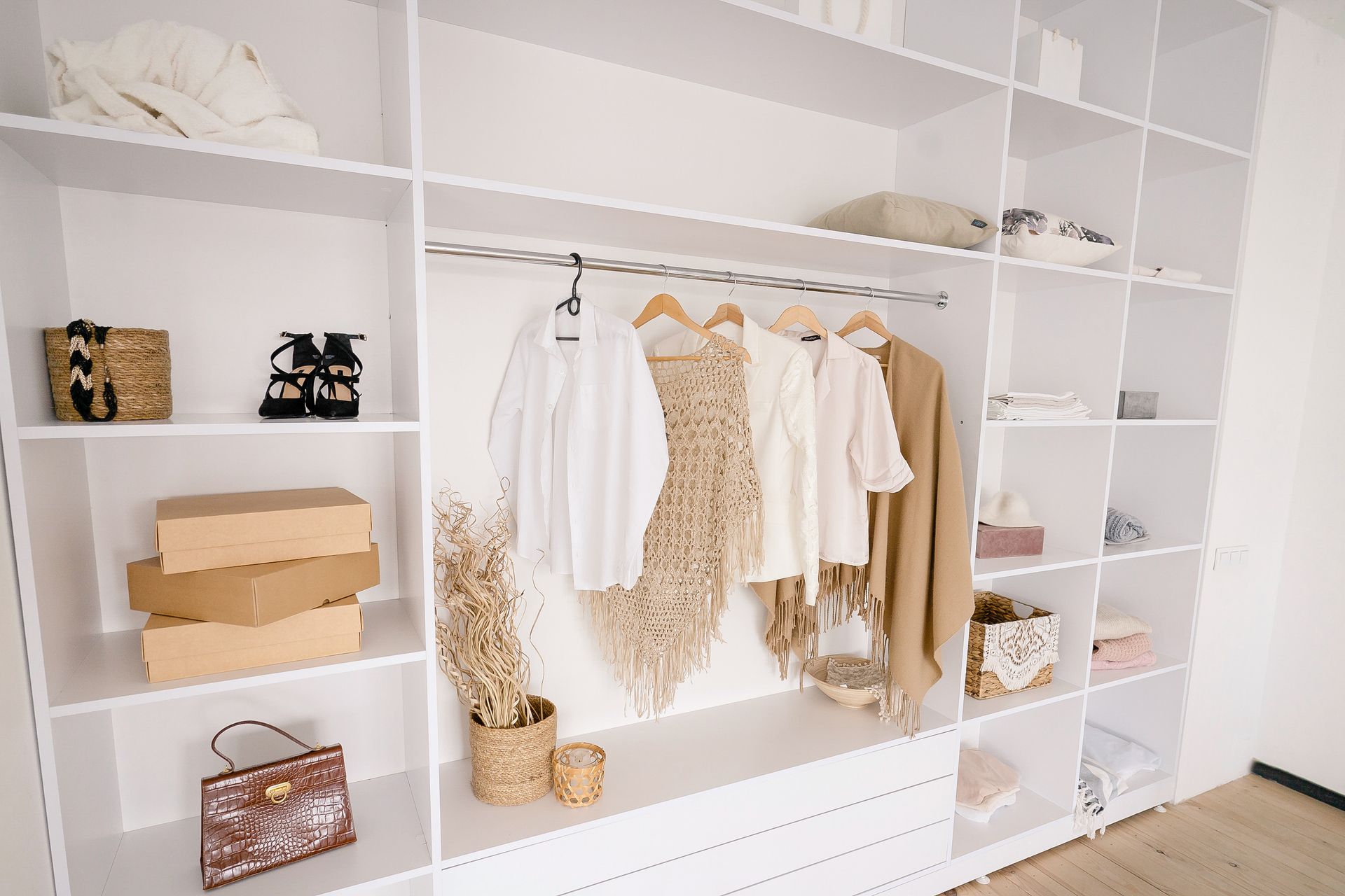 A large white built-in wardrobe stocked with women's clothing, shoes, and accessories.