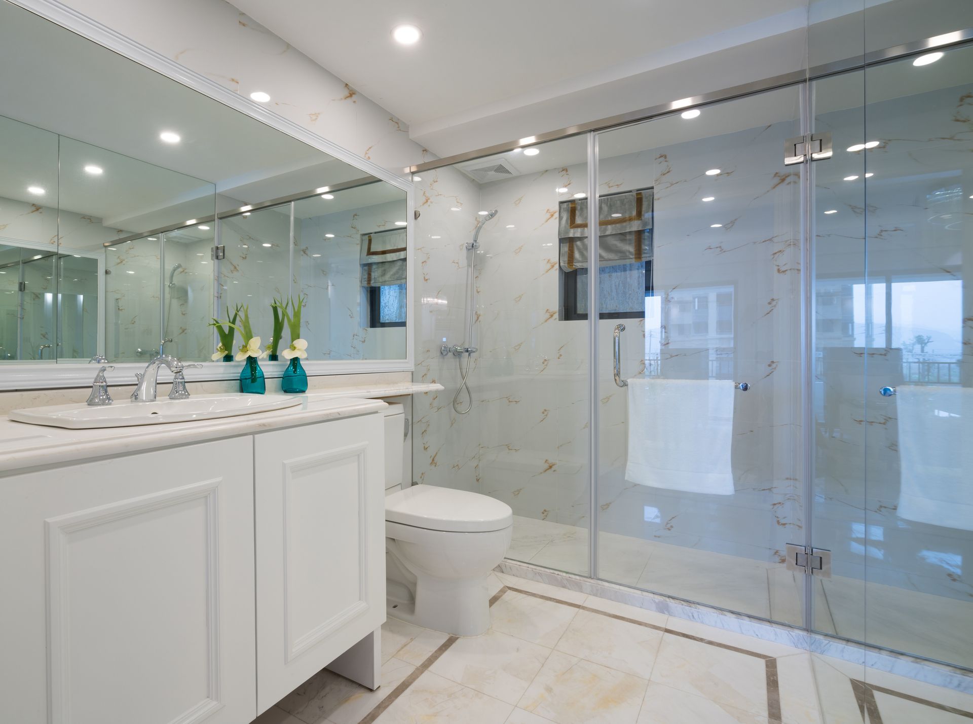 Modern bathroom with large mirrors and glass shower enclosure.