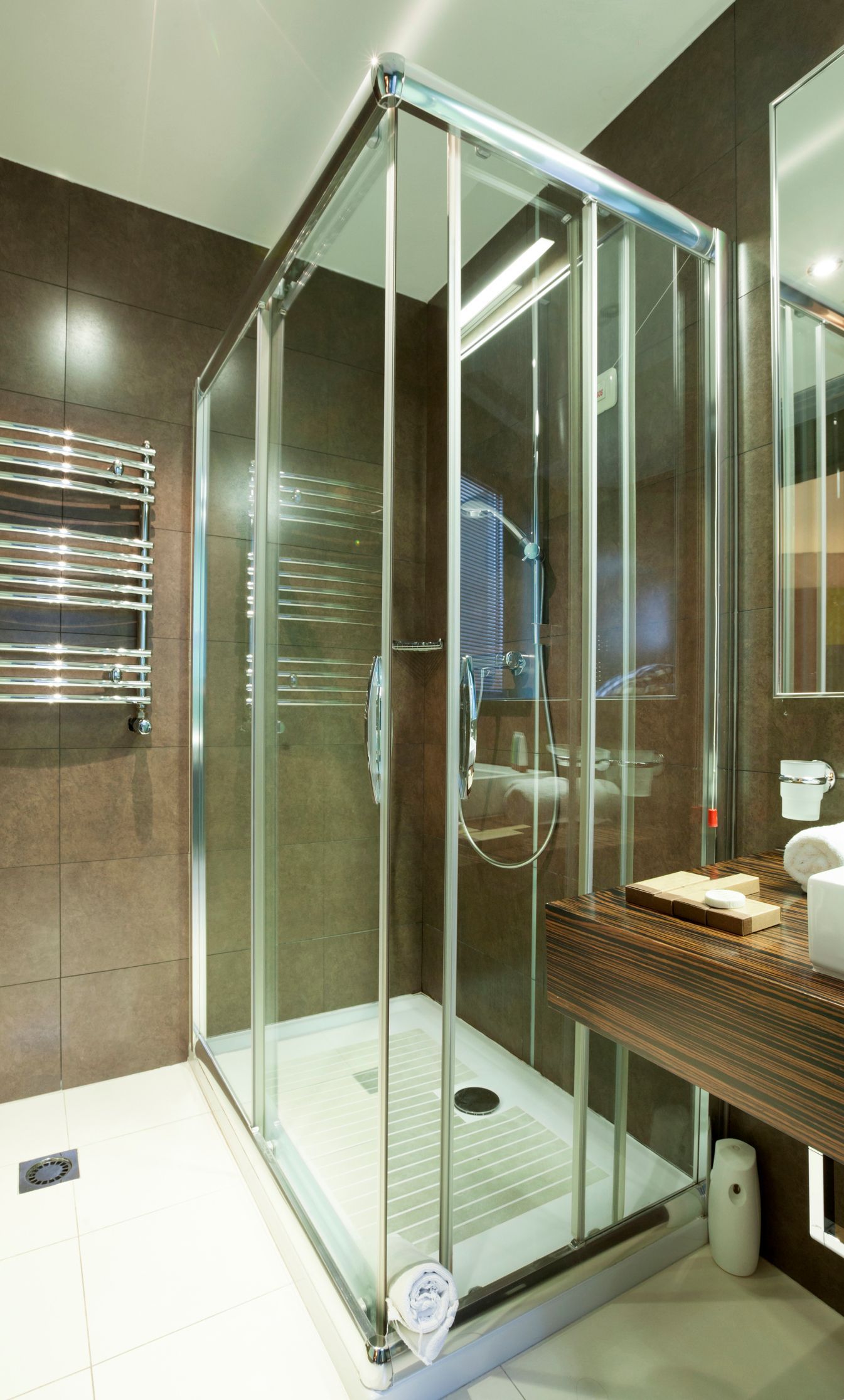 Shower in bathroom with wooden style walls, with a clear shower screen.