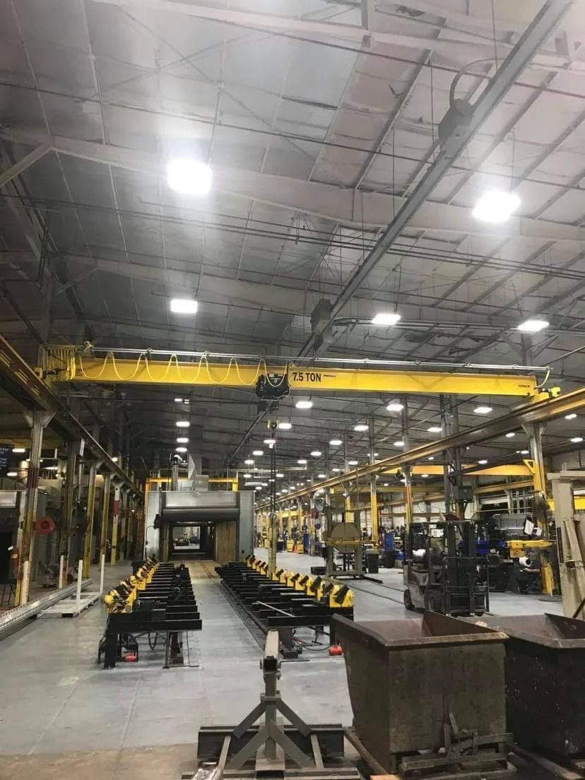 Industrial interior with yellow overhead crane, equipment, and production line.